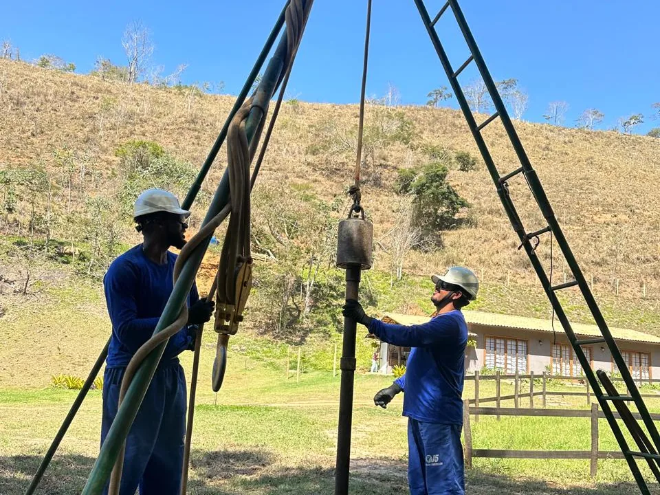 Dois profissionais do Grupo CMG cravando o amostrador SPT em terreno de encosta
